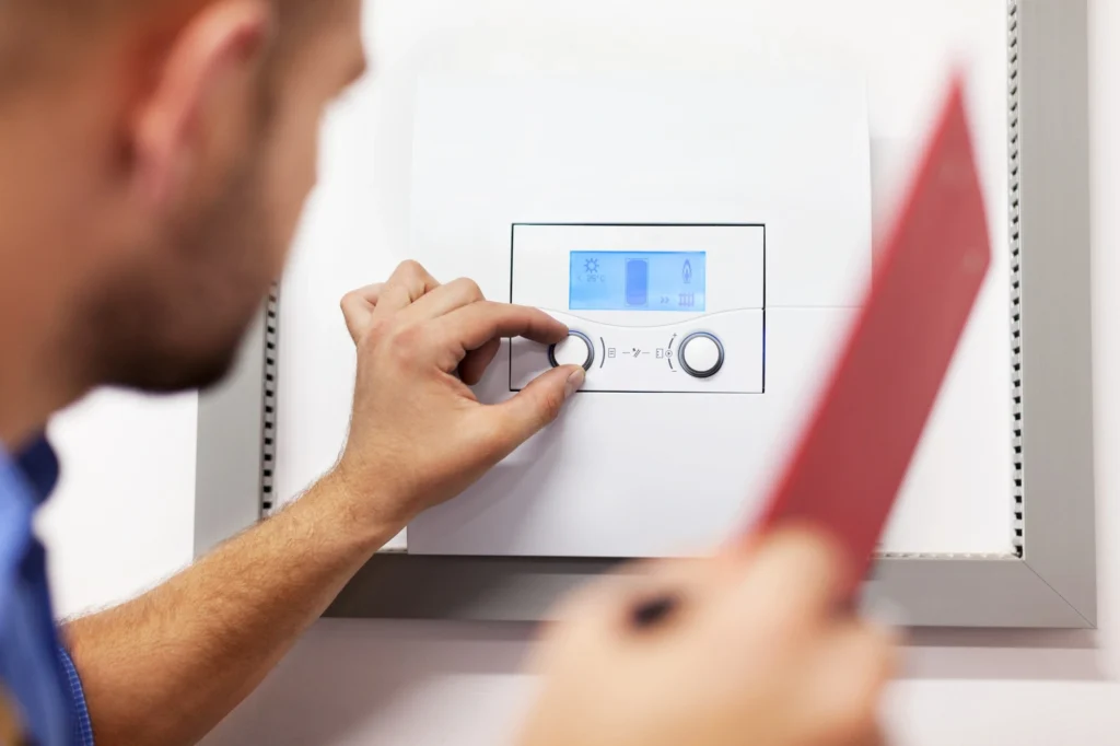 Man adjusts wall-mounted boiler control panel